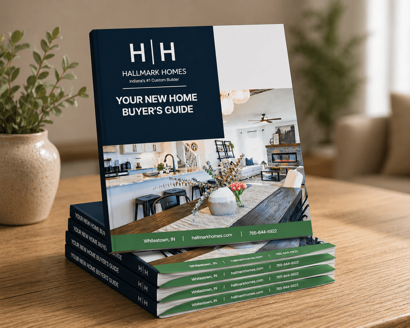 Front cover of a 'Your New Home Buyer’s Guide' brochure by Hallmark Homes on a wooden table, with a potted plant nearby.